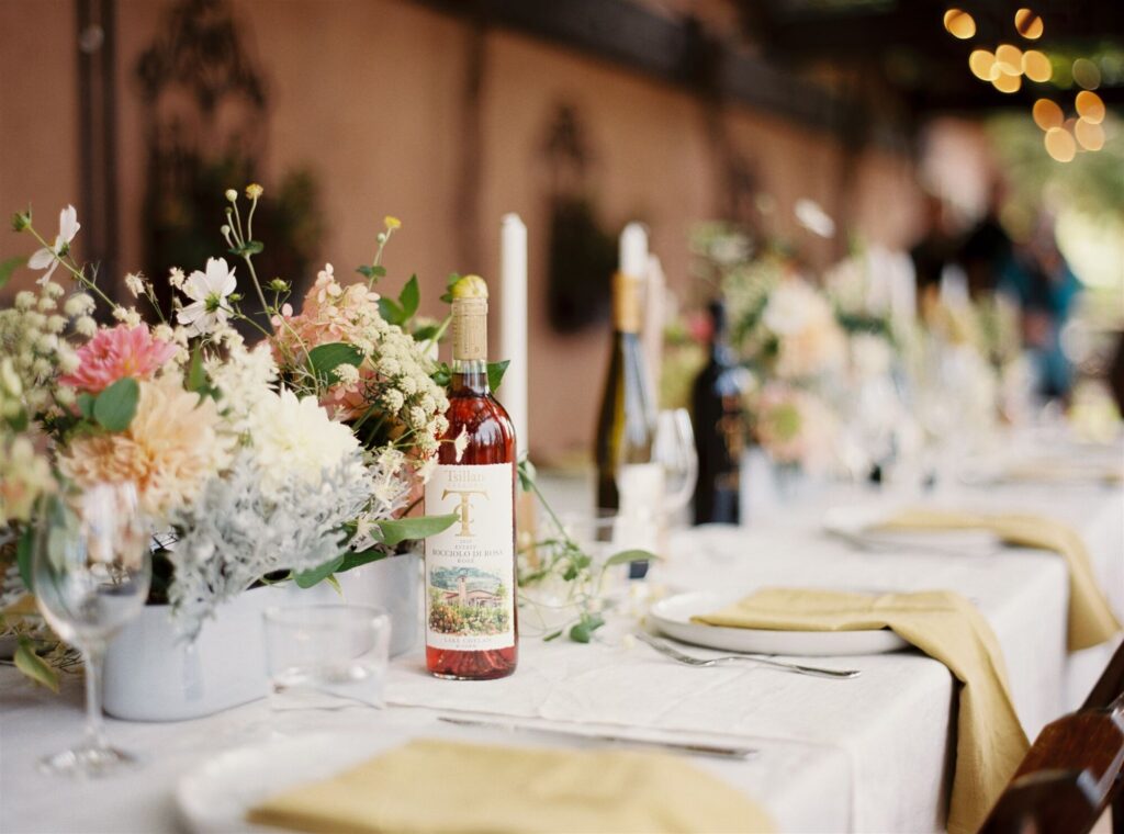 A long wedding table with flowers and estate wine
